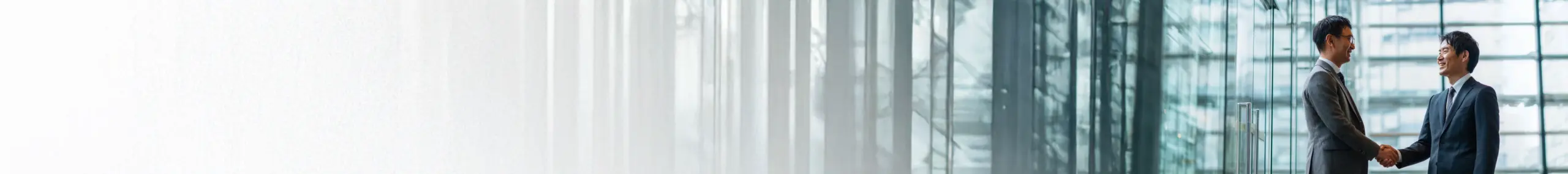 オフィスビルのエントランスで握手する男性二人