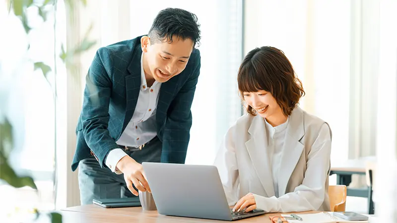 人材育成：経理人材 教育支援イメージ/男性が女性社員のPC入力作業を指導