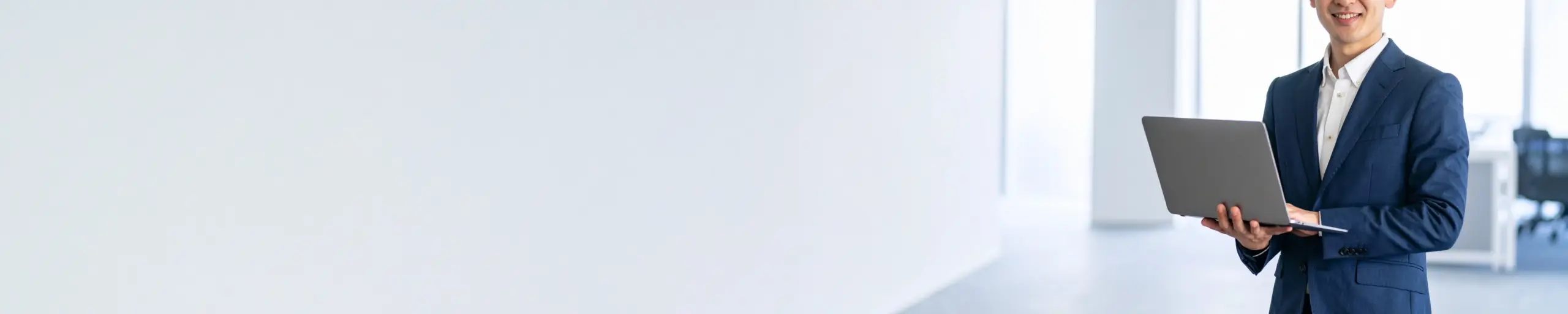 ノートPCを持って微笑む男性