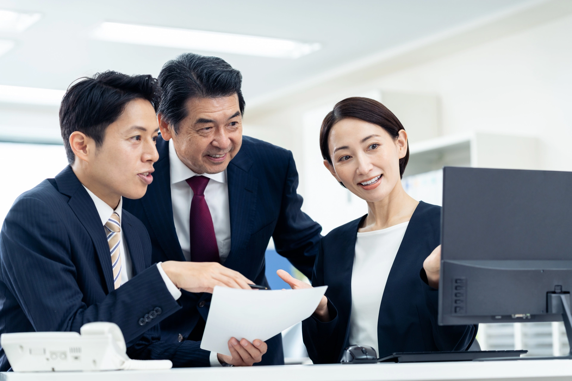 PCを笑顔で覗き込む社長と男女社員