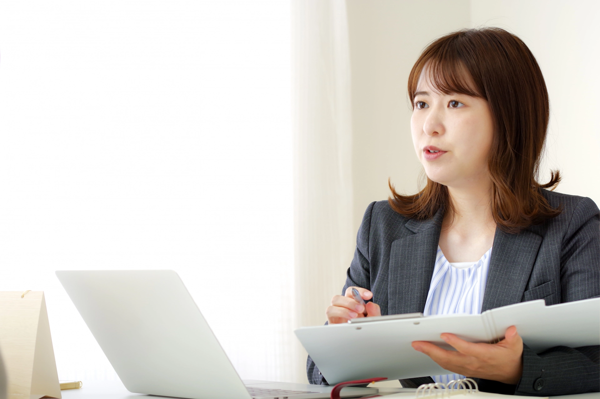 書類片手にPCの前で説明する女性