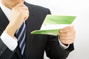 預金通帳を見るビジネスマン